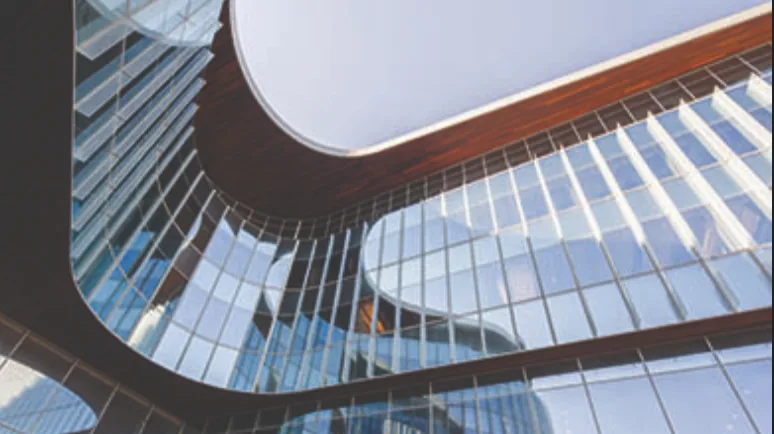 Exterior of Kellogg's Global Hub — sweeping curved glass and warm wood-toned bands against a blue sky.